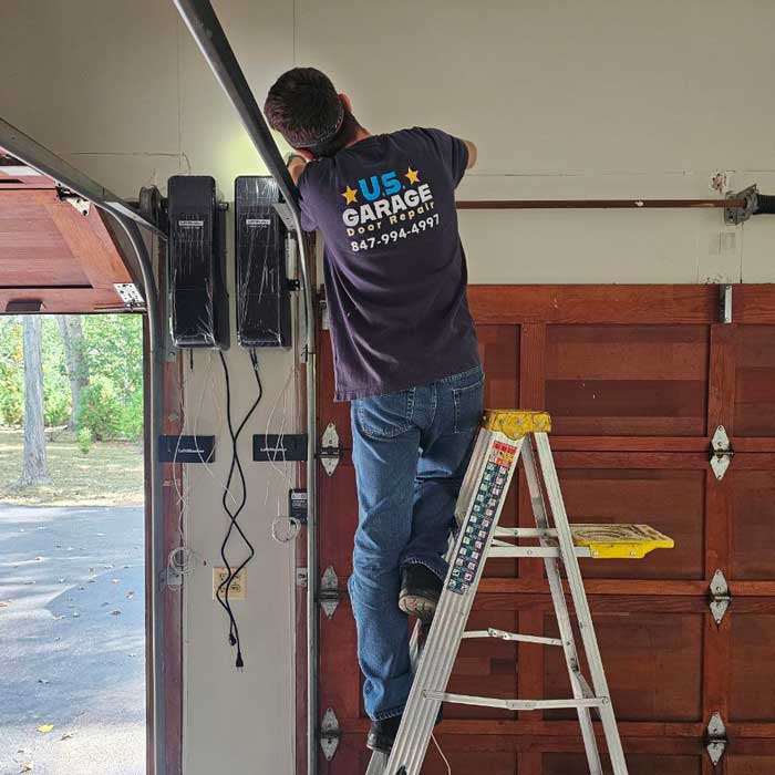 US Garage Door Technician standing on the ladder and fixing garage door near Buffalo Grove, IL